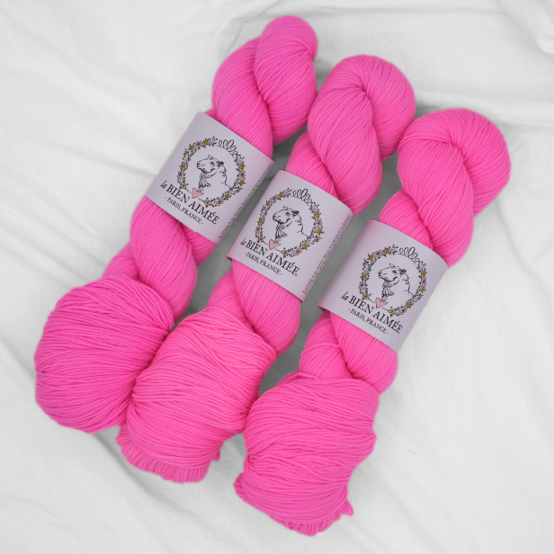 Trzy precle neonowo-różowej włóczki skarpetkowej La Bien Aimee Merino Super Sock w odcieniu Kool